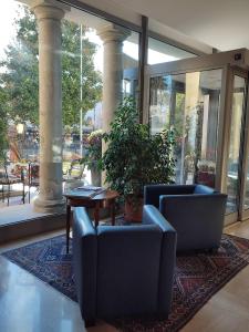 a lobby with two chairs and a table and windows at Hotel Cristallo in Conegliano