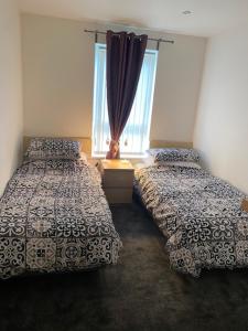 a bedroom with two beds and a window at Doc Y Gogledd in Llanelli
