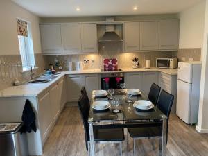 a kitchen with a table and chairs and a kitchen with white appliances at Doc Y Gogledd in Llanelli