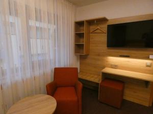 Zimmer mit einem TV, einem Stuhl und einem Tisch in der Unterkunft Gasthof Engel in Dottingen