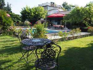 einen Tisch und Stühle in einem Garten mit Pool in der Unterkunft Le clos des Noaillettes in Puybarban