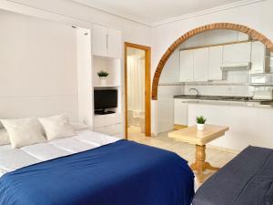 a bedroom with a blue bed and a kitchen at Apartamentos Pagán in Santiago de la Ribera +38 photos