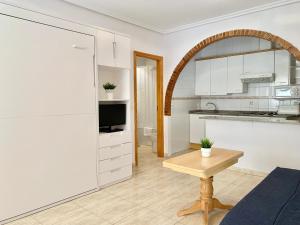 a kitchen with white cabinets and a wooden table at Apartamentos Pagán in Santiago de la Ribera