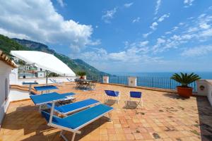 a group of chairs and tables on a patio with the ocean at Villa Aristide Amalfi Coast - POOL in Praiano