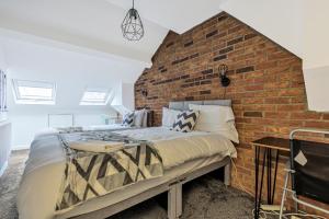Un dormitorio con una pared de ladrillo y una cama en Stylish 5 Bedroom 5 Bathroom House (Sleeps 10) with Garden, Smart TV and Free Parking by Yoko Property en Coventry