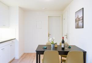 una mesa de comedor con sillas y una botella de vino en HITrental Zur Metzgern Apartments en Luzern