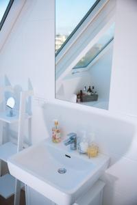 a white bathroom with a sink and a mirror at Flair Appartement Alte Donau in Vienna