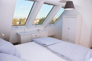 a white bedroom with two windows and a bed at Flair Appartement Alte Donau in Vienna