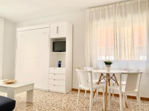 ein weißes Esszimmer mit einem weißen Tisch und Stühlen in der Unterkunft Apartamentos Pagán in Santiago de la Ribera