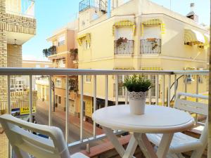 einen Balkon mit einem weißen Tisch und Stühlen sowie ein Gebäude in der Unterkunft Apartamentos Pagán in Santiago de la Ribera