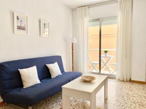 ein blaues Sofa im Wohnzimmer mit einem Tisch in der Unterkunft Apartamentos Pagán in Santiago de la Ribera