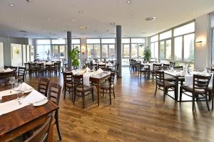 un comedor con mesas, sillas y ventanas en HESSE HOTEL Celle, en Celle