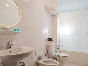 a bathroom with a sink and a toilet and a mirror at Apartamentos Pagán in Santiago de la Ribera