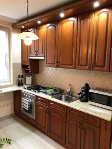a kitchen with wooden cabinets and a sink and a microwave at Oli Apartman in Hajdúszoboszló