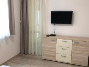 a bedroom with a dresser with a television on the wall at Oli Apartman in Hajdúszoboszló