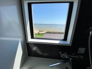 a window above a sink with a view of the ocean at ゴールデンマイルヴィラ in Amami