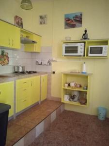 une cuisine avec des armoires jaunes et un four micro-ondes dans l'établissement Le bananier, à Bouillante