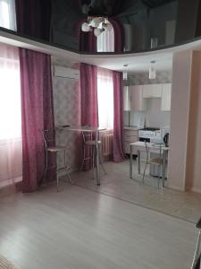a kitchen with pink curtains and a table and chairs at Симбирские апартаменты на Варейкиса 42 in Ulyanovsk