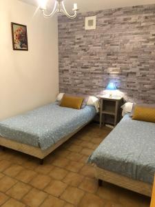 Cette chambre comprend deux lits et une table avec une lampe. dans l'établissement AU MIMOSA - Chambre d'hôte Le Laurier, à Passa