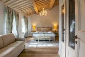 a bedroom with a bed and a couch and a chandelier at Villa La Preziosa in Lucca