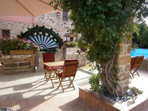 een patio met een tafel en stoelen en een boom bij Mouzaliko Guesthouse Mansion in Kambos