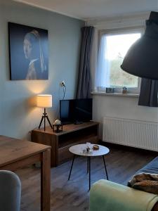 een woonkamer met een bank en een tv bij Bij De Vuurtoren in Hollum