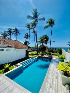 a swimming pool in front of a house with palm trees at SUNSET BEACH HAVEN, Entire Villa, Beachfront, Pool, Private in Galle