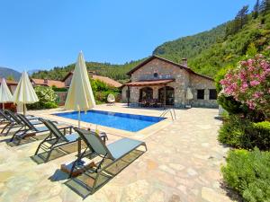 Villa mit einem Pool mit Stühlen und einem Haus in der Unterkunft Villa Kayakoy 2 - Private Stone Villa in Fethiye