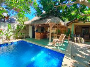 a villa with a swimming pool and a house at Is Oke House in Gili Trawangan
