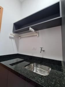 a kitchen counter with a sink and a hood at Lindo Studio frente Mar Matinhos/PR. in Matinhos
