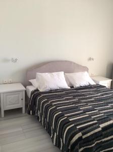 a bedroom with a bed with a striped blanket and two tables at Sailinn Mykonos in Ornos +35 photos
