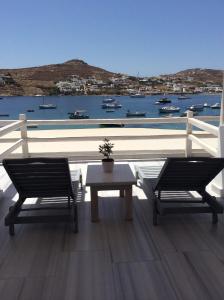 een tafel en stoelen op een balkon met uitzicht op het water bij Sailinn Mykonos in Ornos