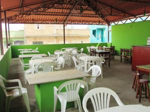 un restaurante con paredes verdes, mesas y sillas blancas en Pousada Fortaleza São Thomé, en São Thomé das Letras
