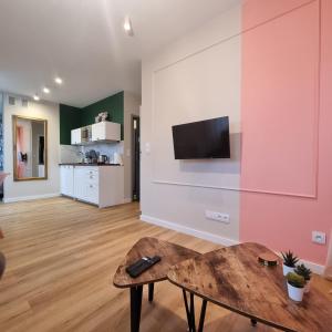 a living room with a table and a tv on a wall at Apartamenty Pastelowe, Suntago, Deepspot, Mszczonów in Mszczonów