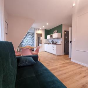 a living room with a green couch and a kitchen at Apartamenty Pastelowe, Suntago, Deepspot, Mszczonów in Mszczonów