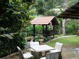 een picknicktafel en stoelen in een achtertuin met een prieel bij Green Season Cottage in Sungai Lembing