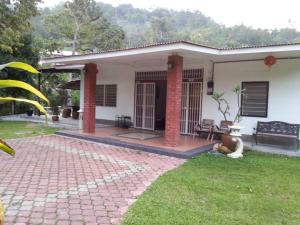 een klein wit huis met een bakstenen patio bij Green Season Cottage in Sungai Lembing