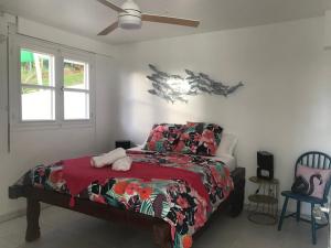 appartement privé ECO-RESPONSABLE, vue sur la mer des Caraibes et jardin clos, WiFi, à 2mn de la plage في سانت لوسي: غرفة نوم بها سرير ومروحة سقف