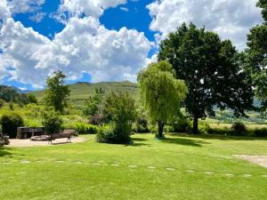 a park with a bench and trees and mountains in the background at Esigodini Cottage in Underberg