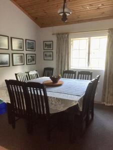 a dining room with a table and chairs and a window at Esigodini Cottage in Underberg