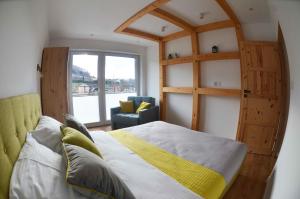 Un dormitorio con una cama y una silla y una ventana. en HARLEY FAMILY APARTAMENT, en Muszyna