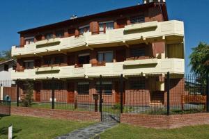 a red brick building with a fence in front of it at Complejo de Mar Wasiyki Villa Gesell in Villa Gesell