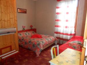 リュス・ラ・クロワ・オートにあるLes 3 Marmottesのベッド2台とテーブルが備わる小さな客室です。