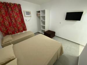 a small room with a bed and a red curtain at Pousada Morada das Nações in Balneário Camboriú
