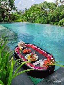 uma mesa com comida numa jangada na água em Kadewa Retreat Ubud - Adults Only em Ubud