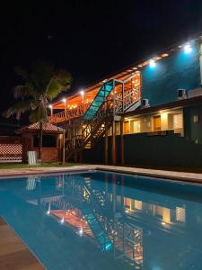 a swimming pool in front of a building at night at Santa Clara Pousada in Guarujá
