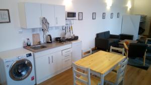 a kitchen with a washing machine and a table at The Uyeasound Old Pier Cottage in Belmont