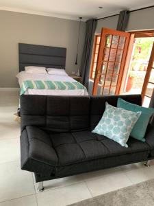 a bed and a couch in a bedroom at Green Pastures Guesthouse in George