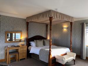 a bedroom with a canopy bed and a chair at Royal Court Hotel in Portrush +155 photos