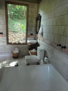 a bathroom with a tub and a toilet and a window at chale opucv in Gonçalves